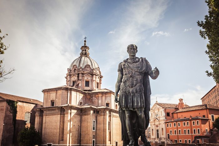 Julius Caesar statue with church of Saint Luca e Martina on the background - a bronze copy of the statue in the Capitol