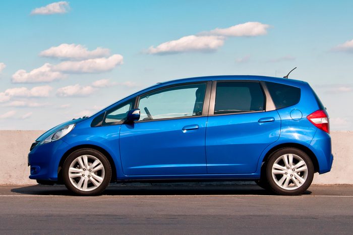 Blue car Honda Jazz parked on the road against the background of the sunny sky. Automotive photography.