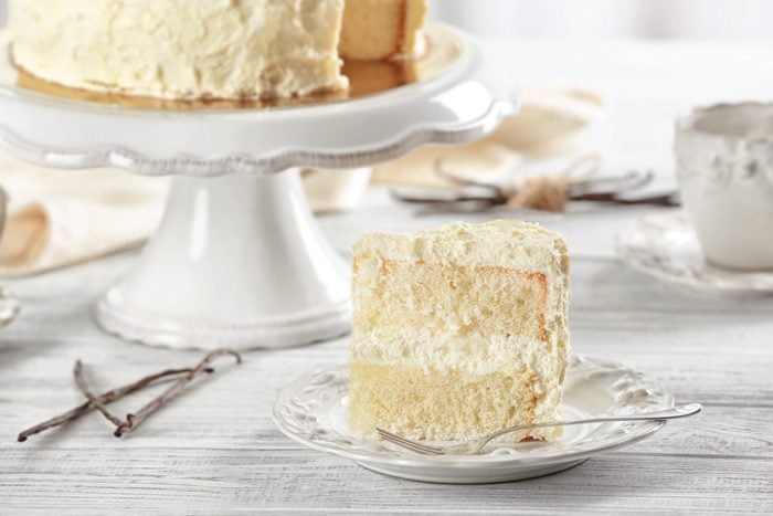 Slice of delicious vanilla cake on wooden table
