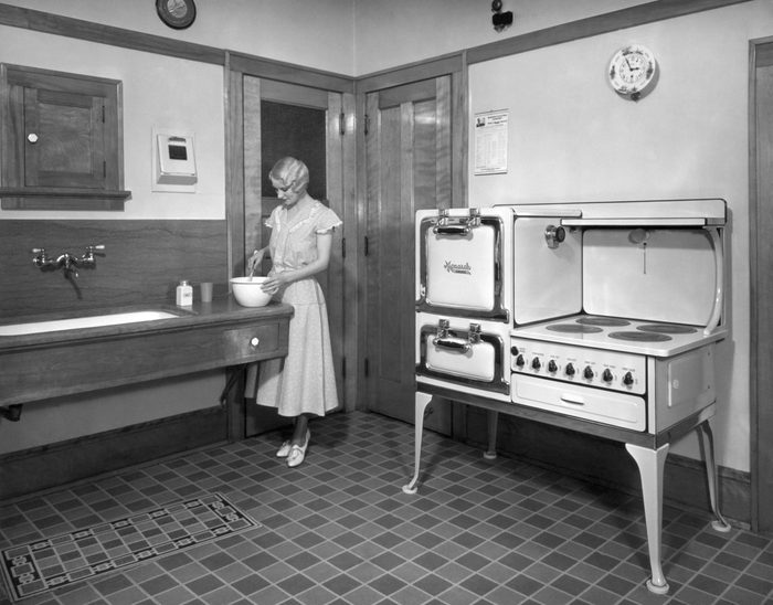 Beaver Dam, Wisconsin: c. 1928. A woman cooking in her kitchen, which is equipped with a Monarch electric stove.