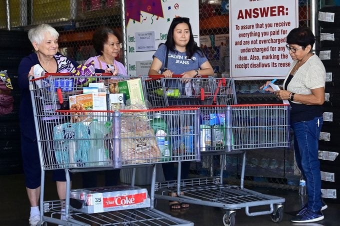 Shoppers have their receipts and trolleys checked by an employee (R) as they exit from a Costco store