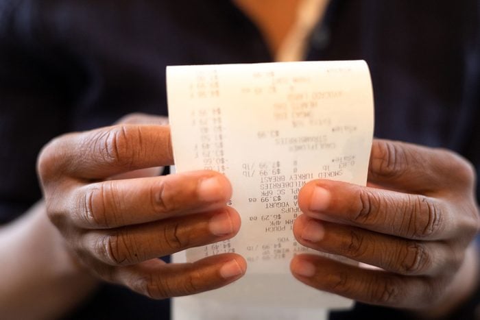 Black Woman Holding Receipt and looking over the purchases