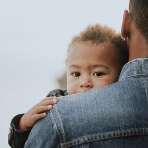 young boy in his dad's arms outdoors. black history month.