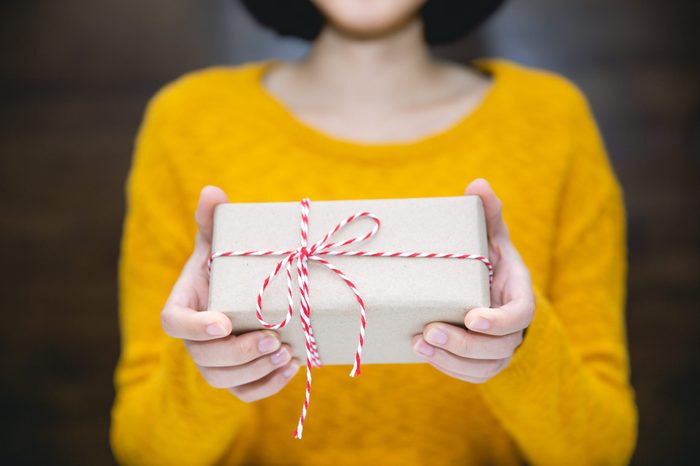 Young woman in yellow sweater holding gift box