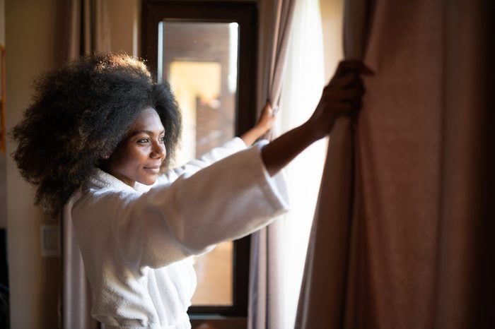 woman pulling open the curtains in a hotel room