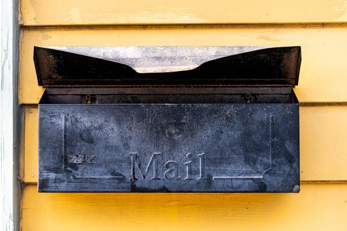 Old retro vintage door mail box, mailbox attached to house home wall exterior painted in yellow color