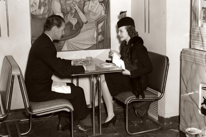 1940s Smiling Young Couple Man Woman Sitting Together On Chrome Art Deco Style Table And Chair Furniture In Modern Cafe