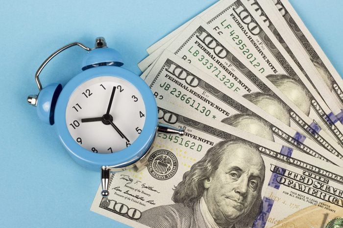 money and alarm clock on a blue background