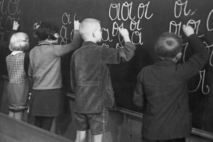 children doing writing exercises on a chalkboard in school. circa 1950