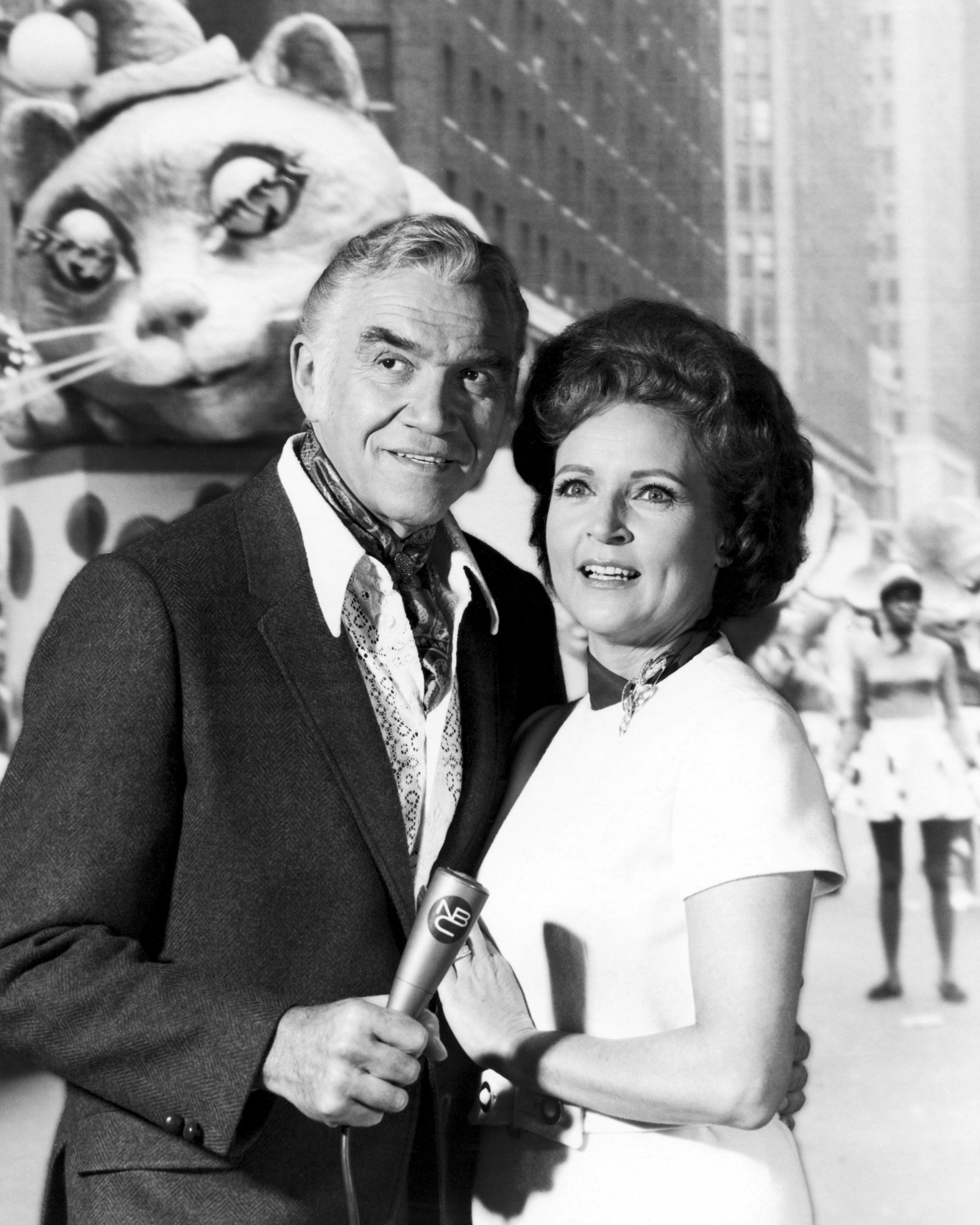 Canadian actor Lorne Greene (1915 - 1987) and American actress Betty White posing for a publicity still, in front of a back projection of a Macy's Thanksgiving Parade, 1969.