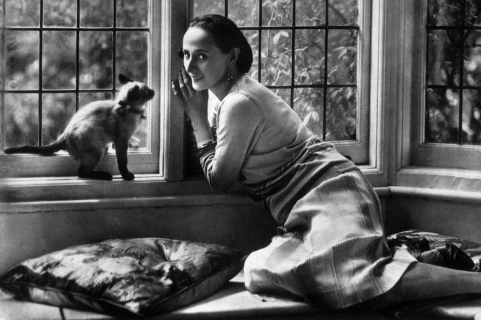 circa 1920: Russian ballet dancer Anna Pavlova (1885 - 1931) relaxing at home with her pet cat
