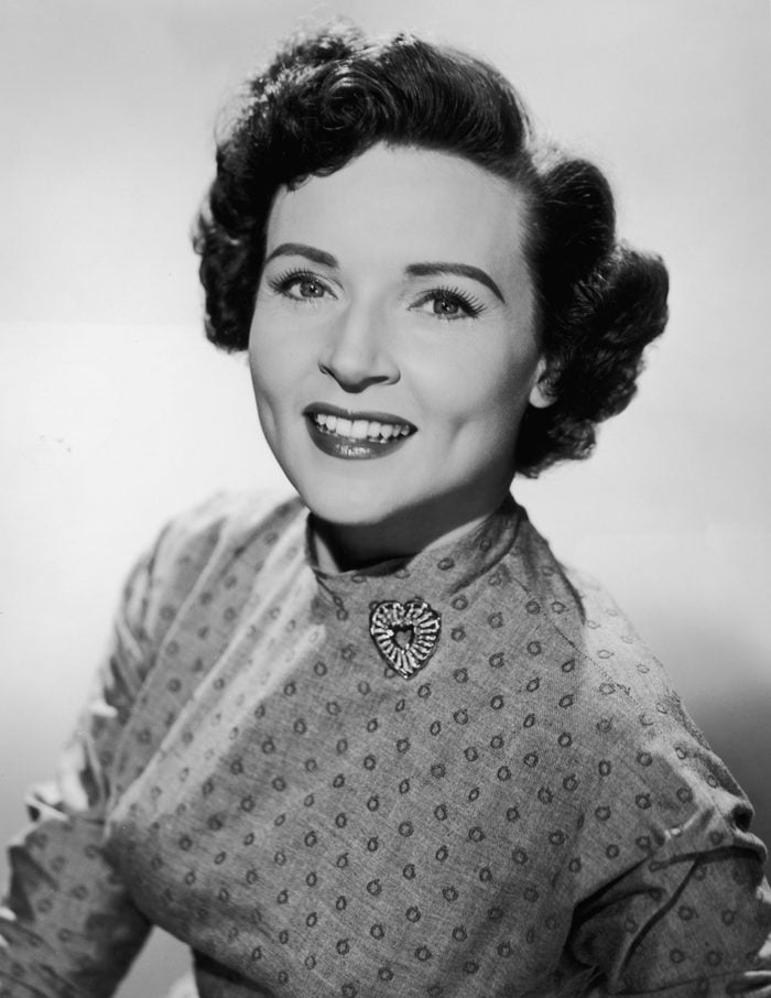 circa 1955: Promotional studio portrait of American actor Betty White smiling and wearing a patterned dress with a heart-shaped brooch.