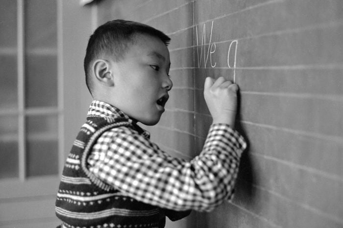 young boy writing on a chalkboard circa 1955