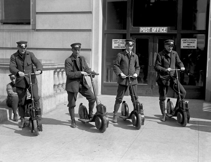 Four special delivery postmen for the US Postal Service try out new scooters, mid 1910s.