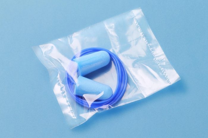 blue ear plugs with blue cord wrapped in plastic on blue background