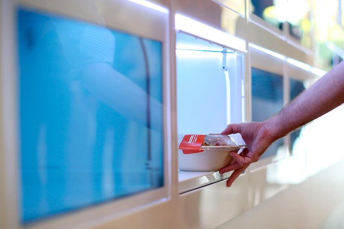 a hand reaches into an automated cubbie to get his food
