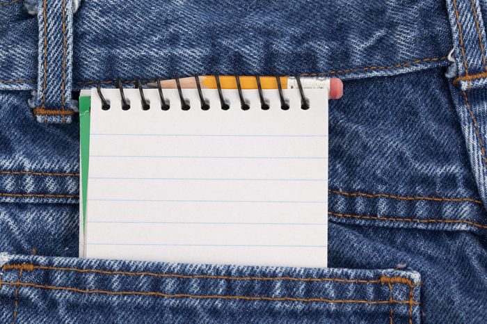 Blank lined notebook and a small pencil in the back pocket of denim jeans.