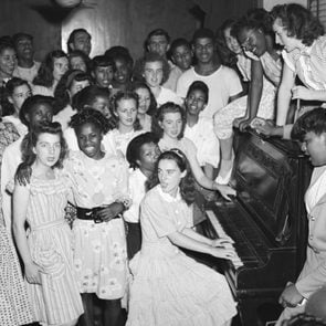 black women and white women surrounding a piano