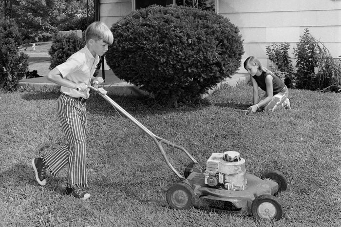 1970s BROTHER AND SISTER DOING CHORES MOWING LAWN CUTTING GRASS YARD WORK TOGETHER