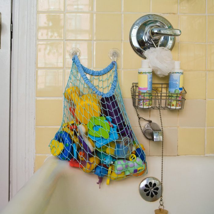 mesh bag of bath toys hanging on suction cup wall hooks