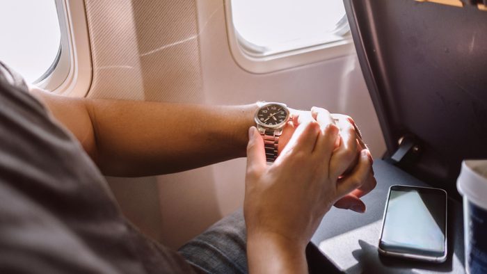 man looking at his watch in an airplane