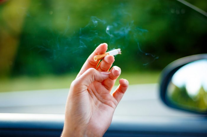 hand holding a cigarette over the windowsill of a car