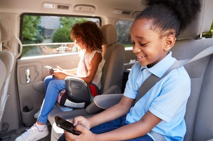 children in booster seats using devices in the car