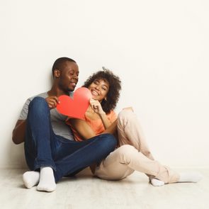 Young happy african-american couple in love holding red paper heart