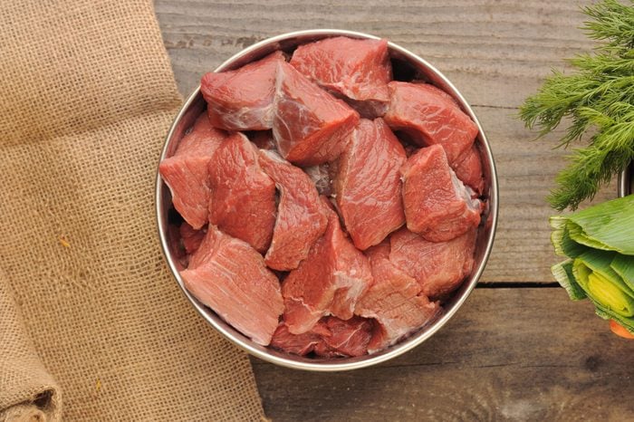 raw beef in dog bowl on wooden background