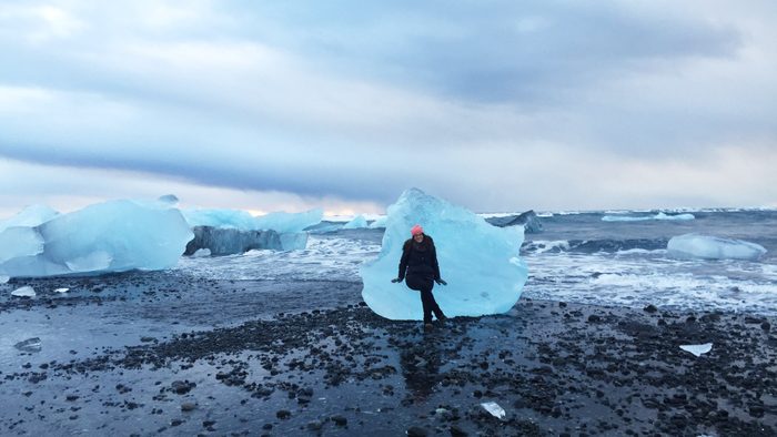 Madeline Wahl sitting on an iceberg on a beach in iceland