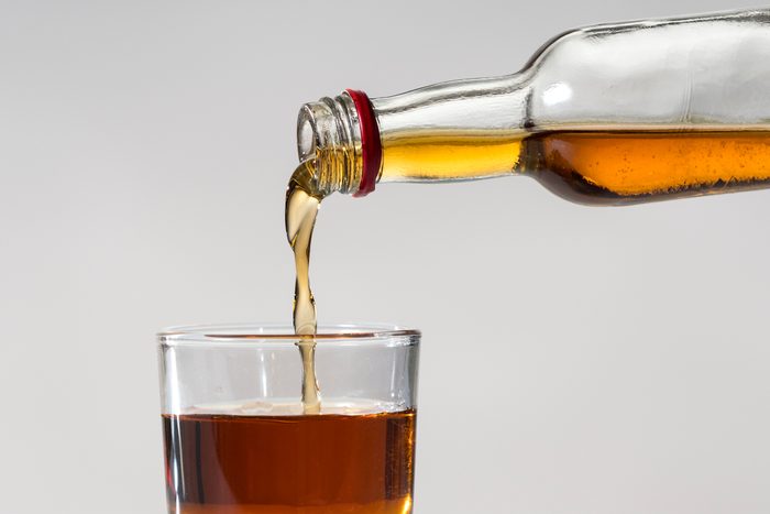 alcohol being poured into a glass on a grey background