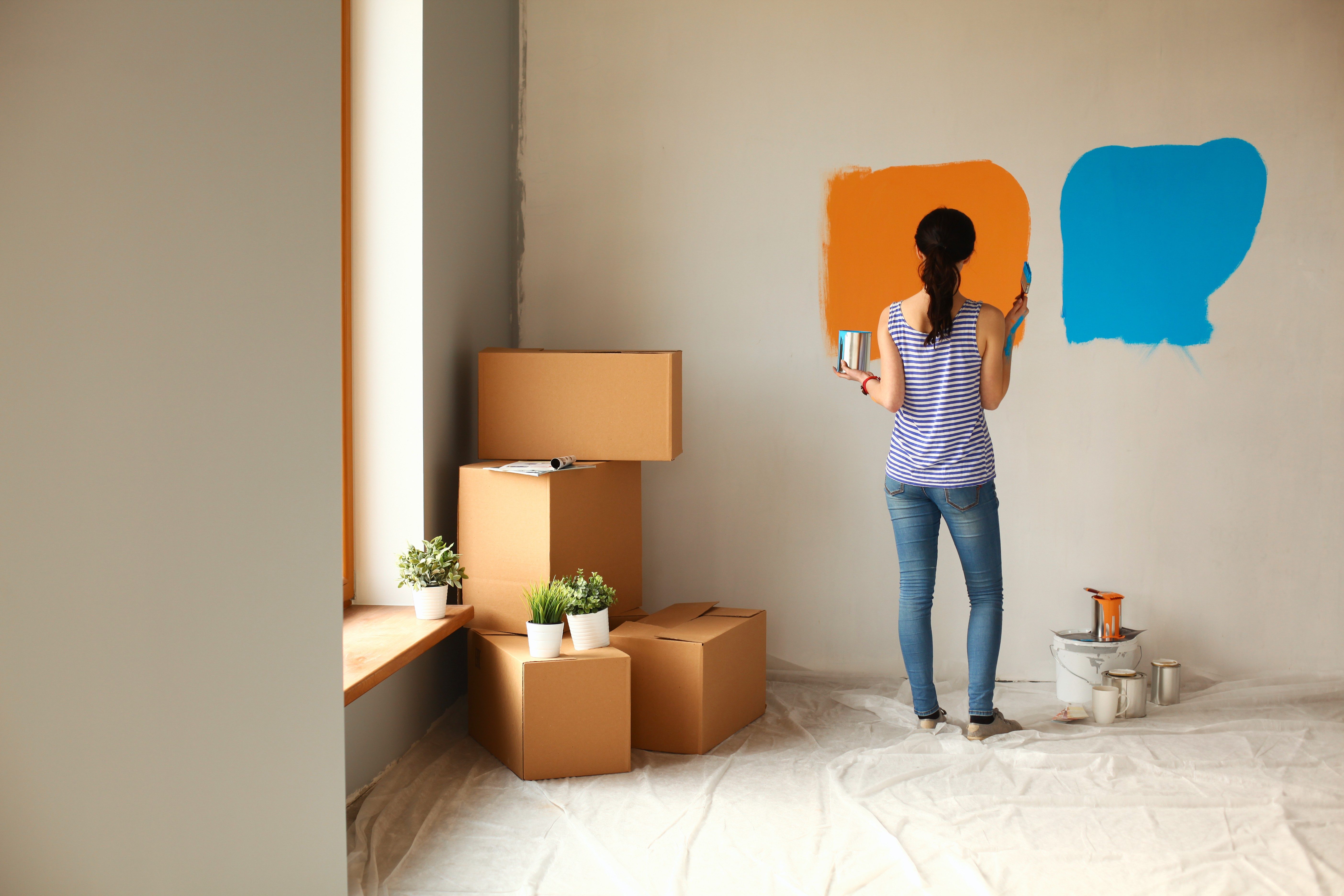 Happy smiling woman painting interior wall of new house