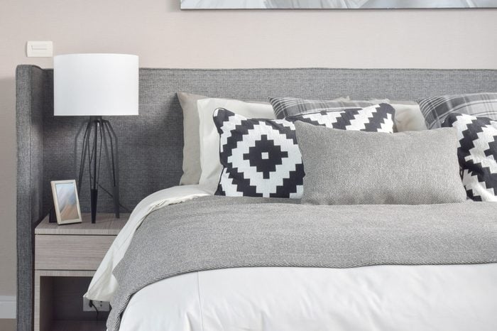 Graphic pattern and grey shade pillows on the bed with modern style reading lamp