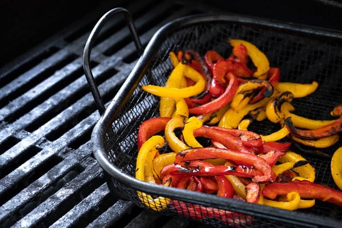 Charred yellow and red bell peppers, in a barbecue grill basket