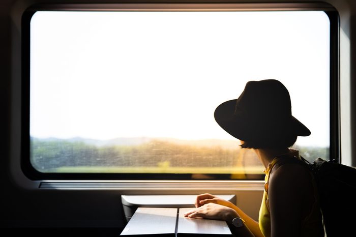 A beautiful hipster asian woman travelling on the train. Sitting on the black leather cozy comfort seat in the business class boky of the train in Europe. Tourist travel concept.