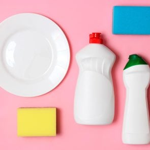 dish washing aids, sponges and a plate on a colored background, top view. Housework, wash the dishes. flatlay