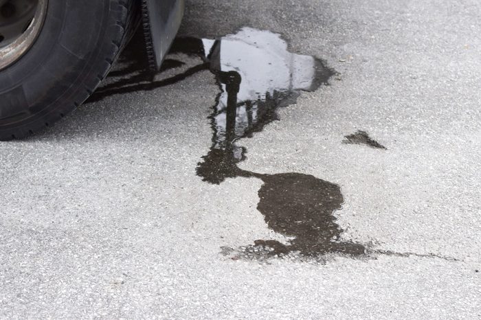 Oil stain on the pavement under the car. Dirty asphalt under the car.