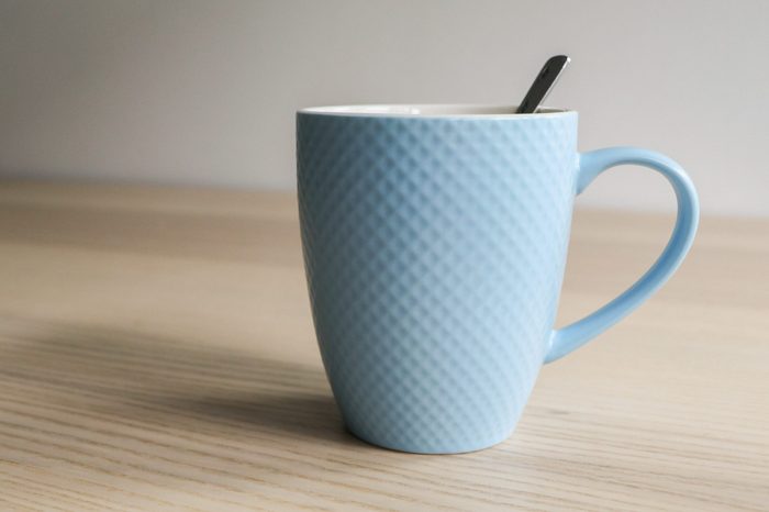 Blue mug with spoon on wooden table