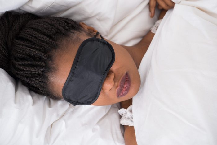 African Woman Wearing Eyemask While Sleeping On Bed