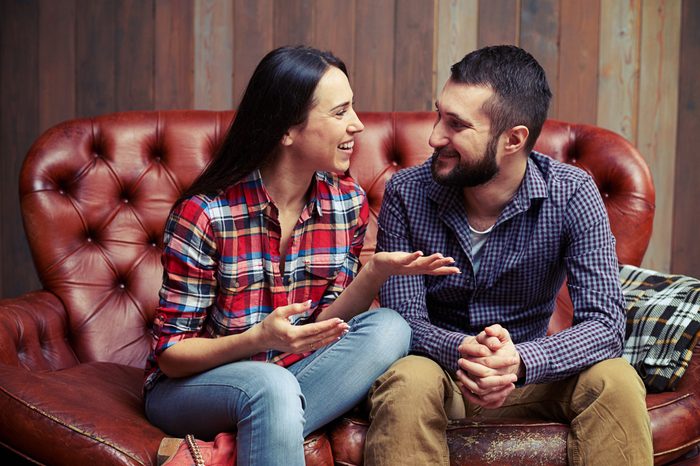 smiley couple sitting on couch and have a nice conversation at home
