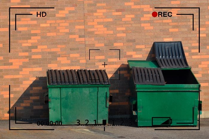garbage dumpsters next to brick wall with camera info overlay