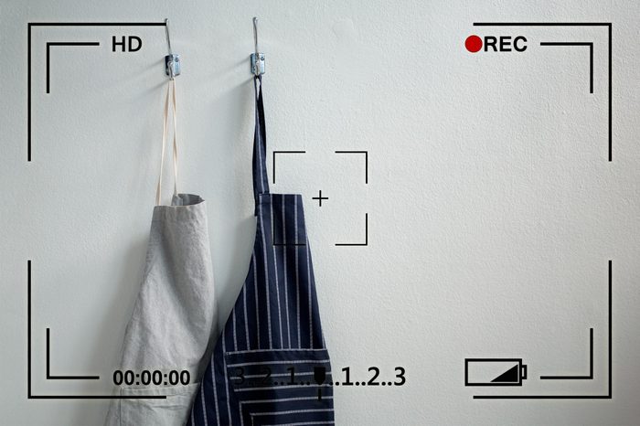 two aprons hanging on hooks on a white wall with camera info overlay