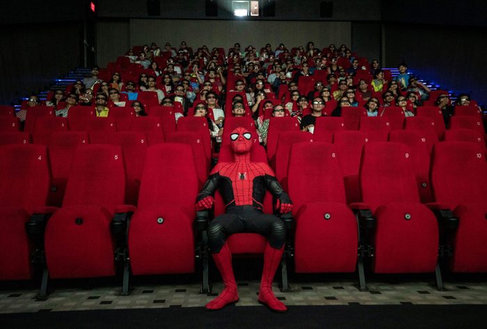 spiderman sits in the front row of a movie theater
