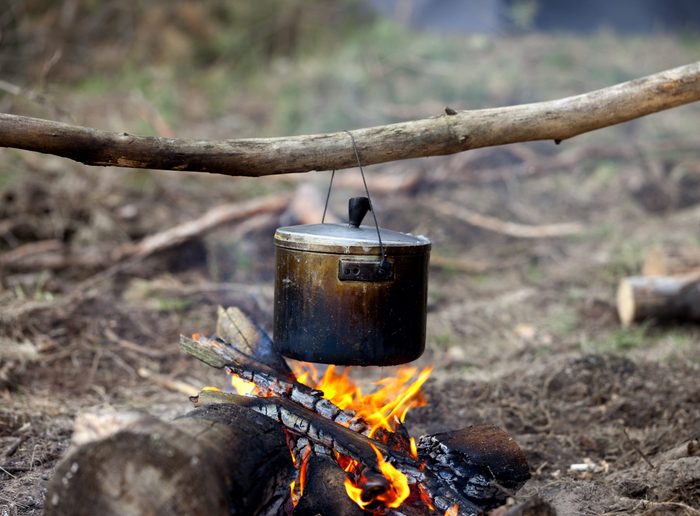 Cooking in sooty cauldron on campfire at forest