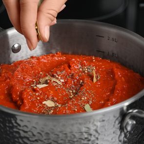 Woman cooking delicious tomato sauce in pan on stove