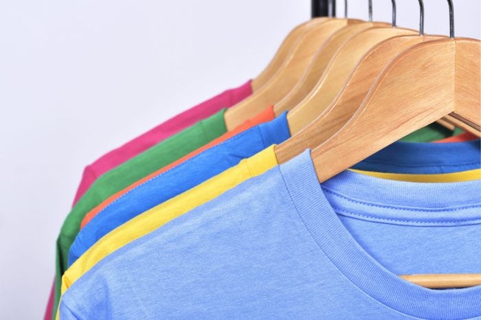 colorful tshirts hanging on a rack on wooden hangers