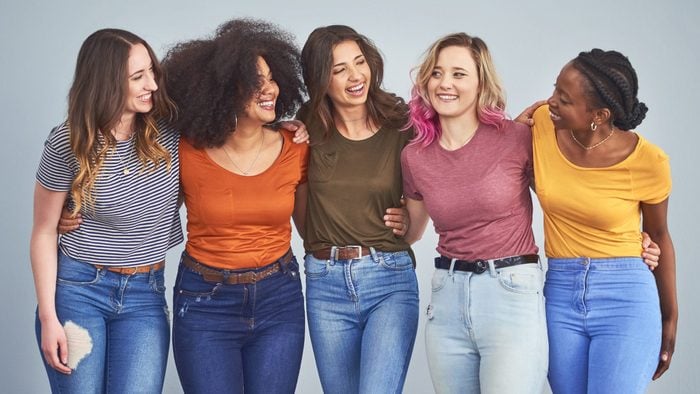 Studio shot of a group of diverse young women embracing against a gray background