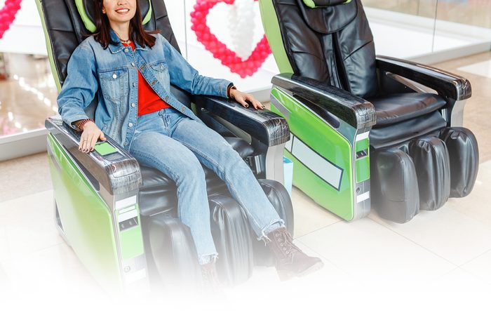 woman relaxing in a coin operated massage chair in an airport