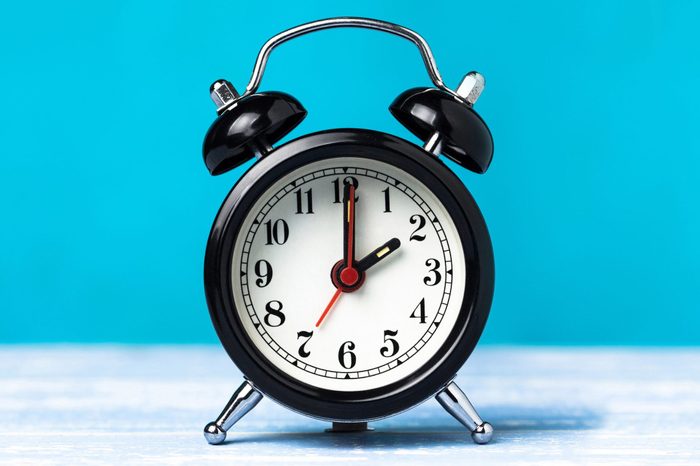 Retro black alarm clock on blue background; clock reads 2 o'clock am