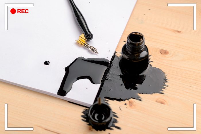 spilt black calligraphy ink on paper and desk.